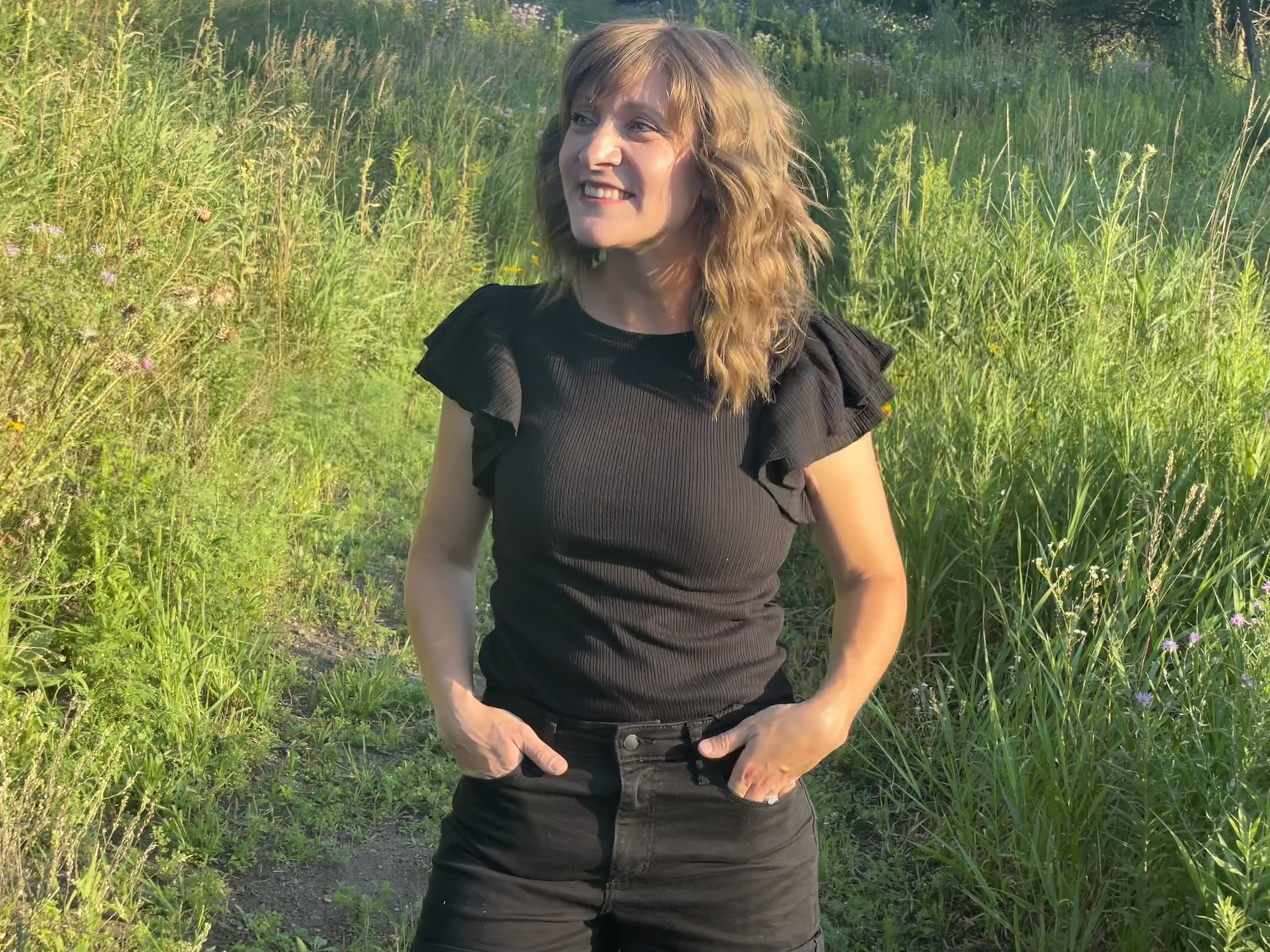 Early intervention teacher smiling and singing songs for communication in a green grassy field